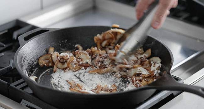 adding flour to cooked onions to a pan 