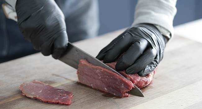 slicing eye of round beef on a cutting board