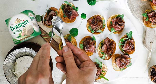 adding cheese to a steak appetizer on a chip