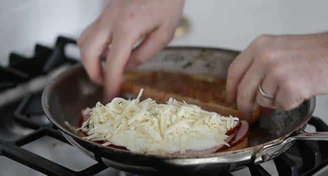 sprinkling Comte cheese onto a slice of bread