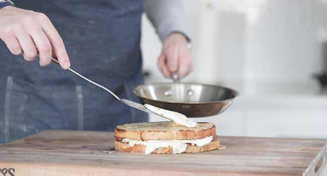 placing a fried egg on top of a croque madame sandwich