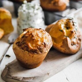 popovers on a cutting board with herb butter