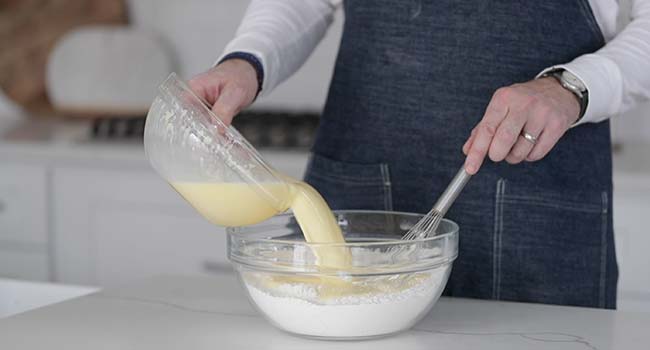 adding wet ingredients to a bowl of dry ingredients