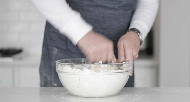 cutting butter with flour in a bowl using a pastry knife