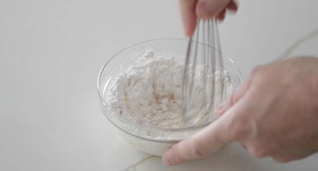 whisking together powdered sugar and milk in a bowl