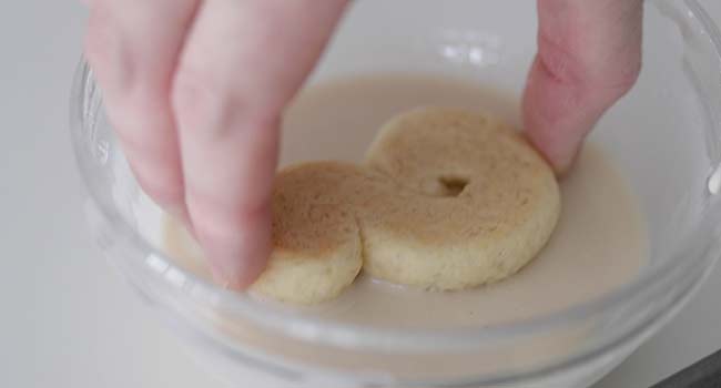 dipping baked s cookies into powdered sugar glaze