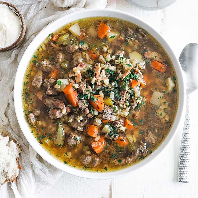 bowl of beef and barley soup with herbs