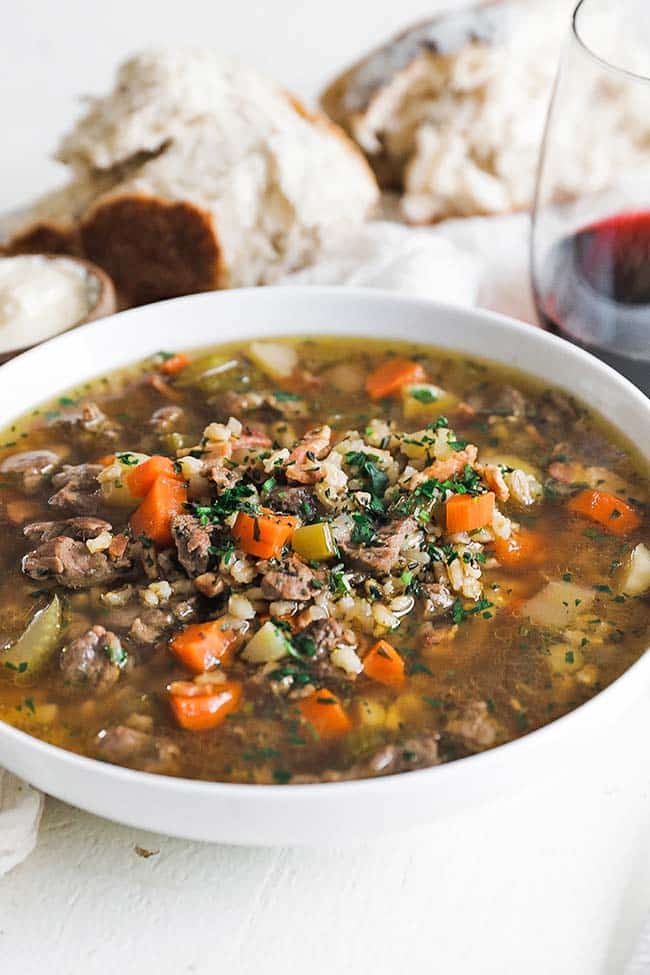 bowl of beef stew and barley with herbs and bread