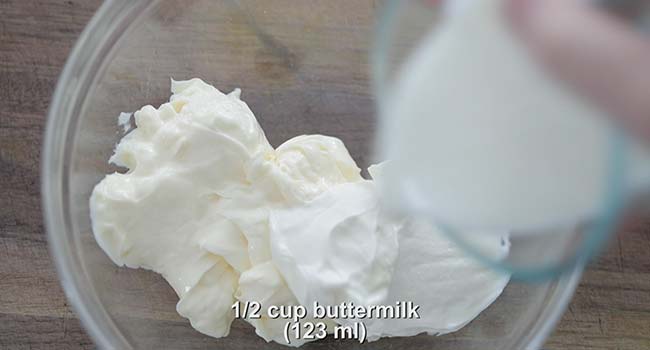 adding sour cream to a bowl with mayonnaise