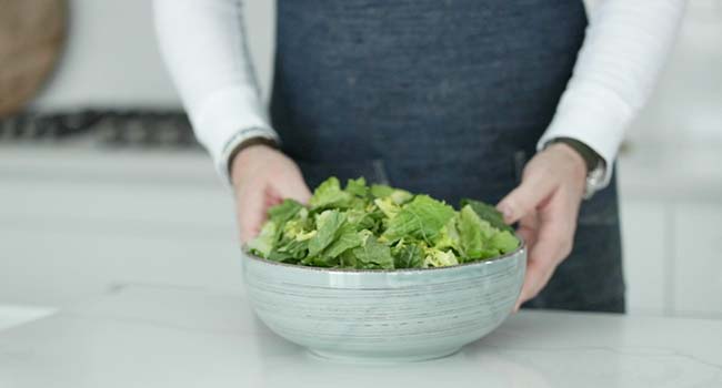 adding lettuces to a large bowl