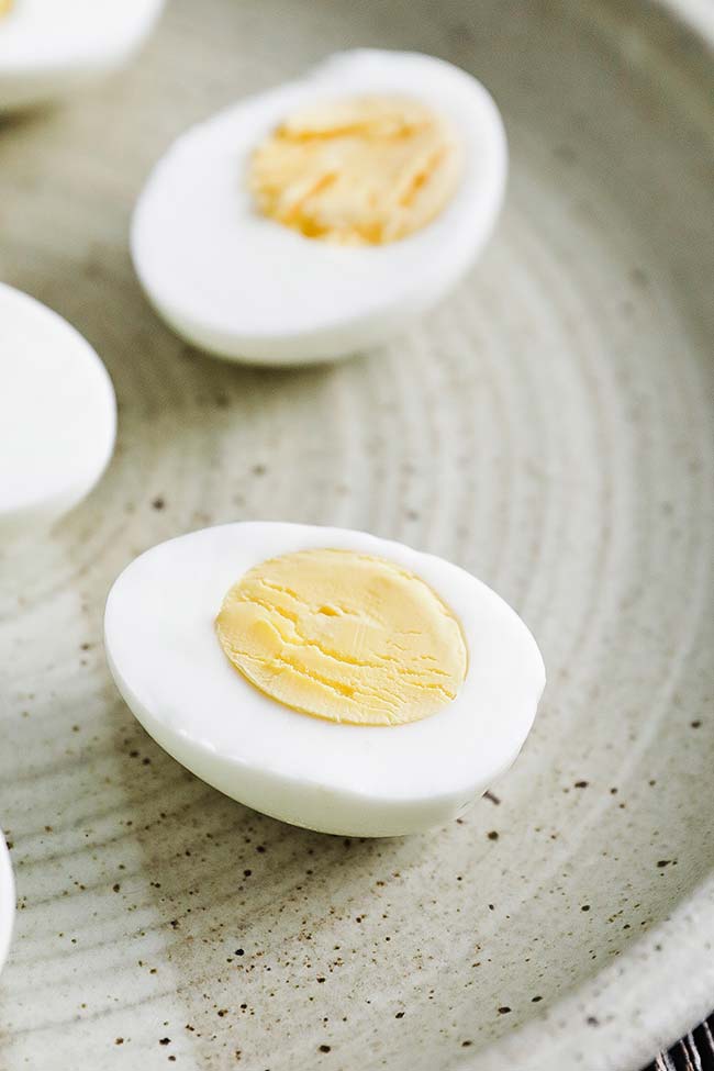 a peeled hard boiled egg sliced in half on a plate