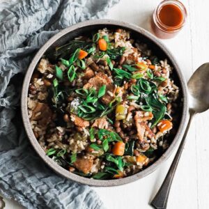 bowl of hoppin john with hot sauce and a spoon