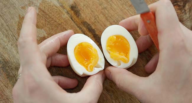 sliced medium boiled eggs on a cutting board