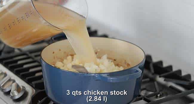 adding chicken stock to a pot of potatoes