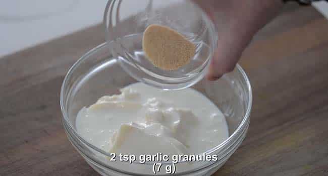 adding spices to a bowl of buttermilk and mayonnaise
