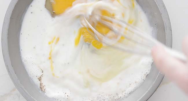 whisking together eggs and milk in a pan