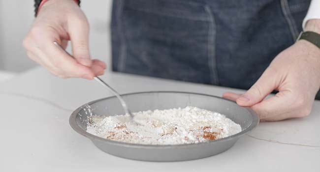 mixing flour and spices in a pan with a fork