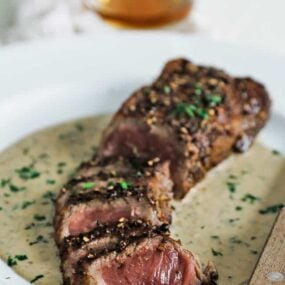 sliced steak au poivre with cream sauce on a plate