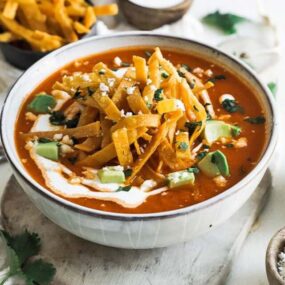 bowl of tortilla soup with crema and avocado