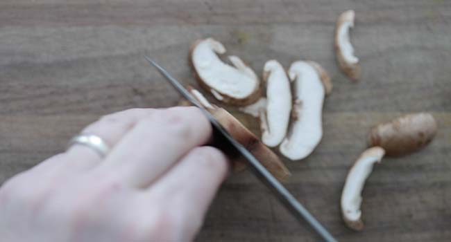 slicing mushrooms on a cutting board