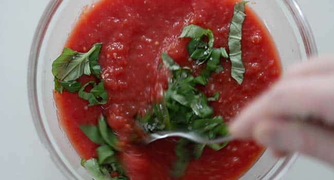 mixing fresh basil with diced tomatoes