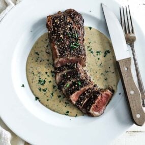 sliced steak au poivre with cream sauce on a plate