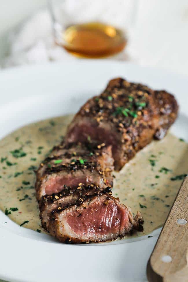 sliced steak au poivre with cream sauce on a plate