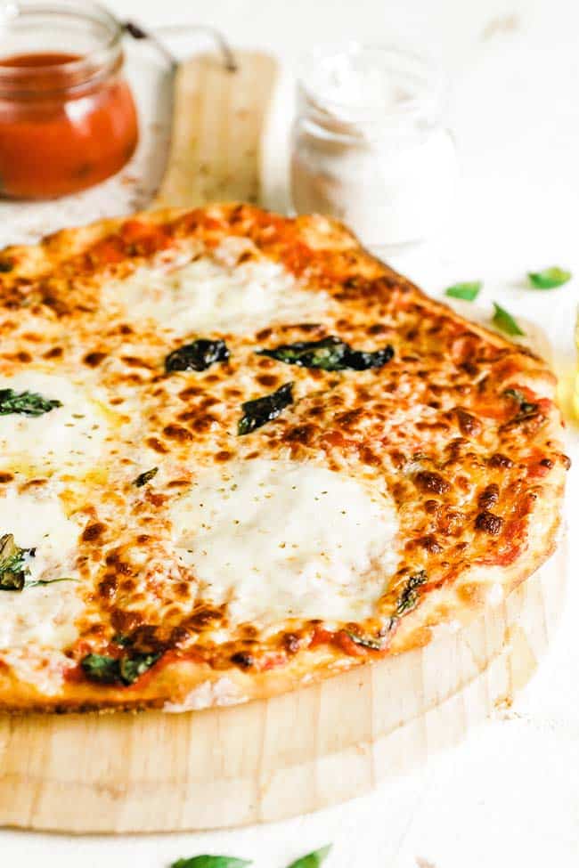 thin crust pizza recipe on a pizza peel with mozzarella slices