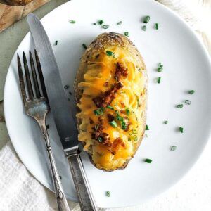 a twice baked potato with chives on a plate