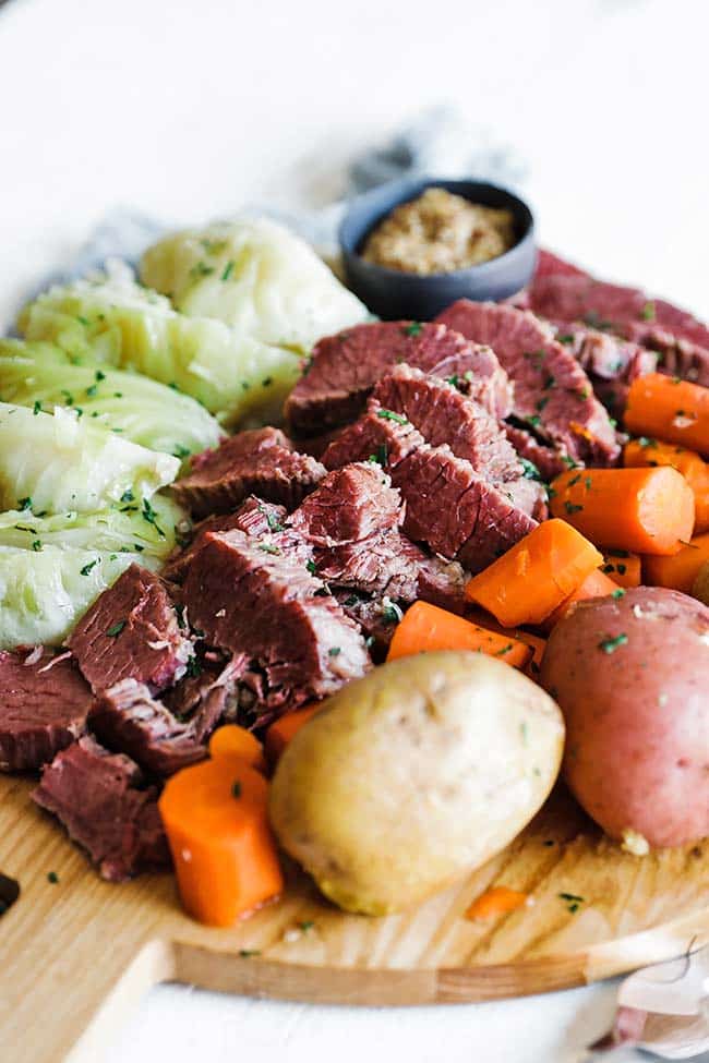 bread board full of cooked potatoes, carrots, cabbage, and corned beef