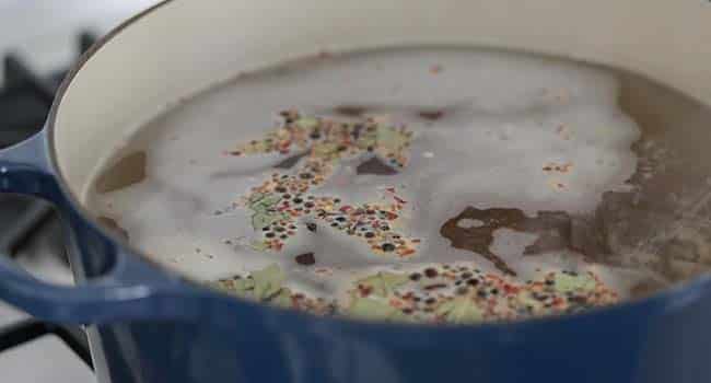 boiling together water, salt, and pickling spice together in a pot