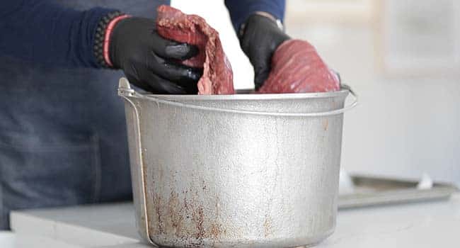 adding a raw brisket to a pot of cooled brine