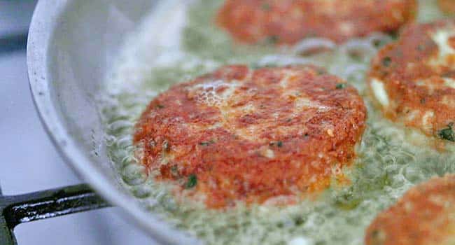 frying crab cakes in oil in a pan