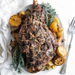 a roasted leg of lamb with lemons and potatoes