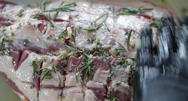 coating a leg of lamb in herbs and garlic