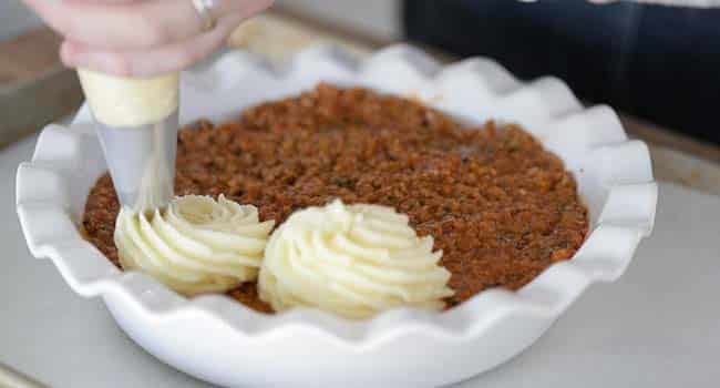 adding mashed potatoes to the top of shepherd's pie stuffing