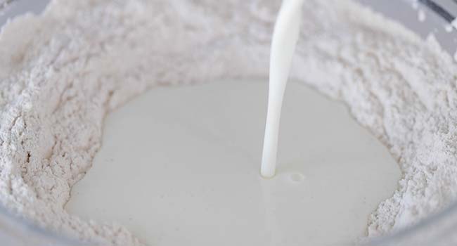 pouring milk into a well of flour