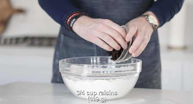 adding raisins to soda bread batter in a bowl