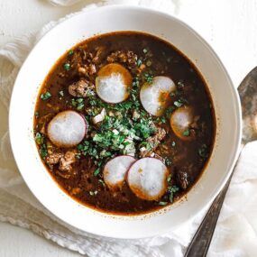 bowl of birria consome with radishes and cilantro