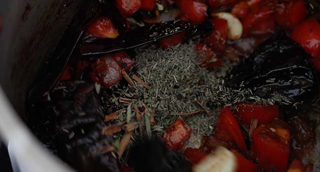 dried herbs and spices with tomatoes and peppers in a pot