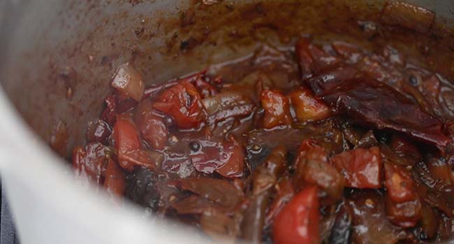 birria braising liquid in a pot with tomatoes and peppers