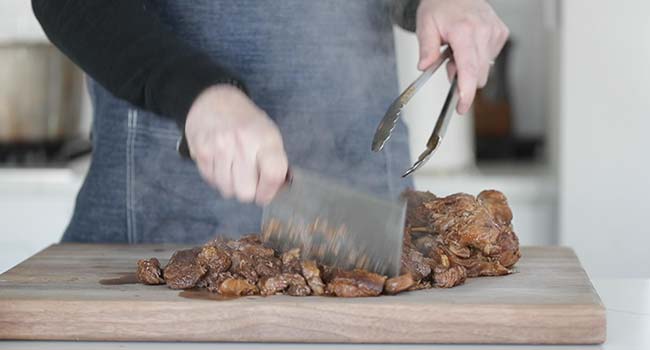 chopping birria meat on a cutting board