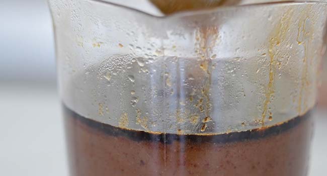 straining birria consome through a chinois