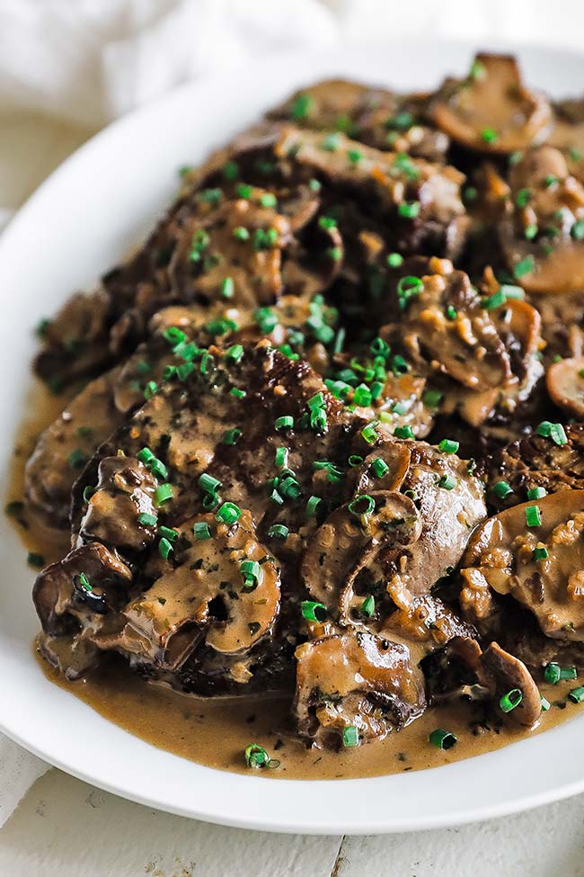 white plate with pan seared steak diane with creamy mushroom sauce