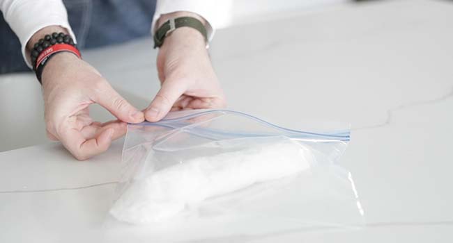 placing a damp paper towel with fresh herbs into a plastic bag