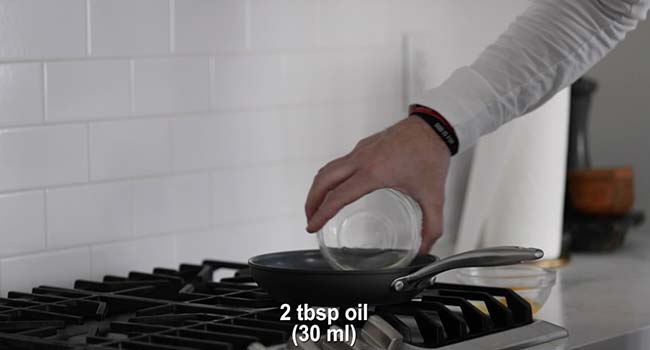 adding an egg to a hot frying pan