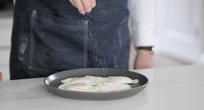 seasoning fried eggs on a plate