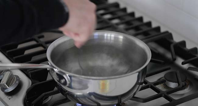 stirring hot water in a pot with a spoon