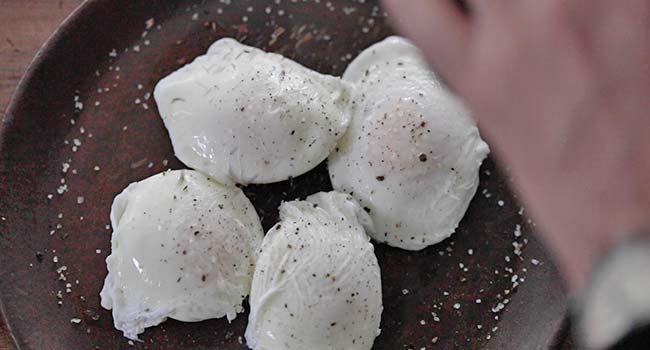 seasoning poached eggs on a plate