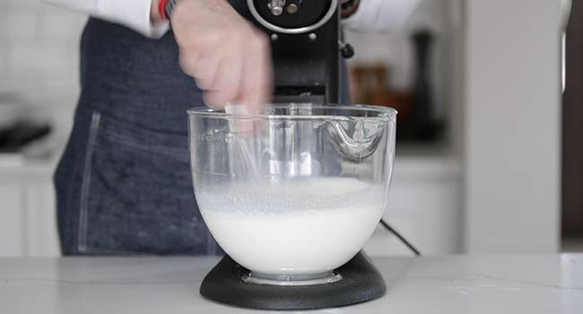 whisking milk and yeast in a stand mixer bowl